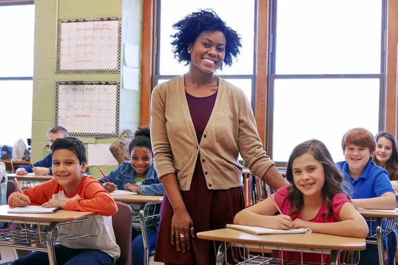 A female teacher poses in her classroom.