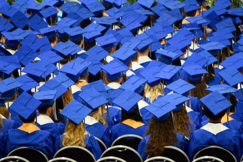  A large group of graduates wearing blue caps and gowns.
