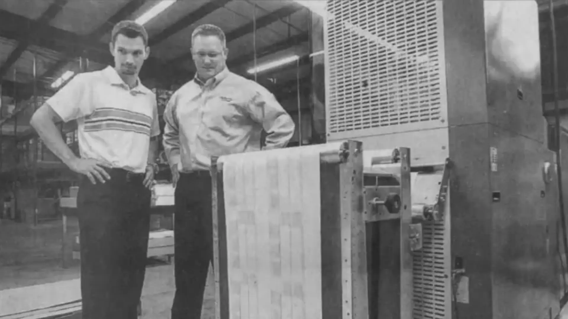 Photo from a newspaper article of two employees watching a datebook being printed.
