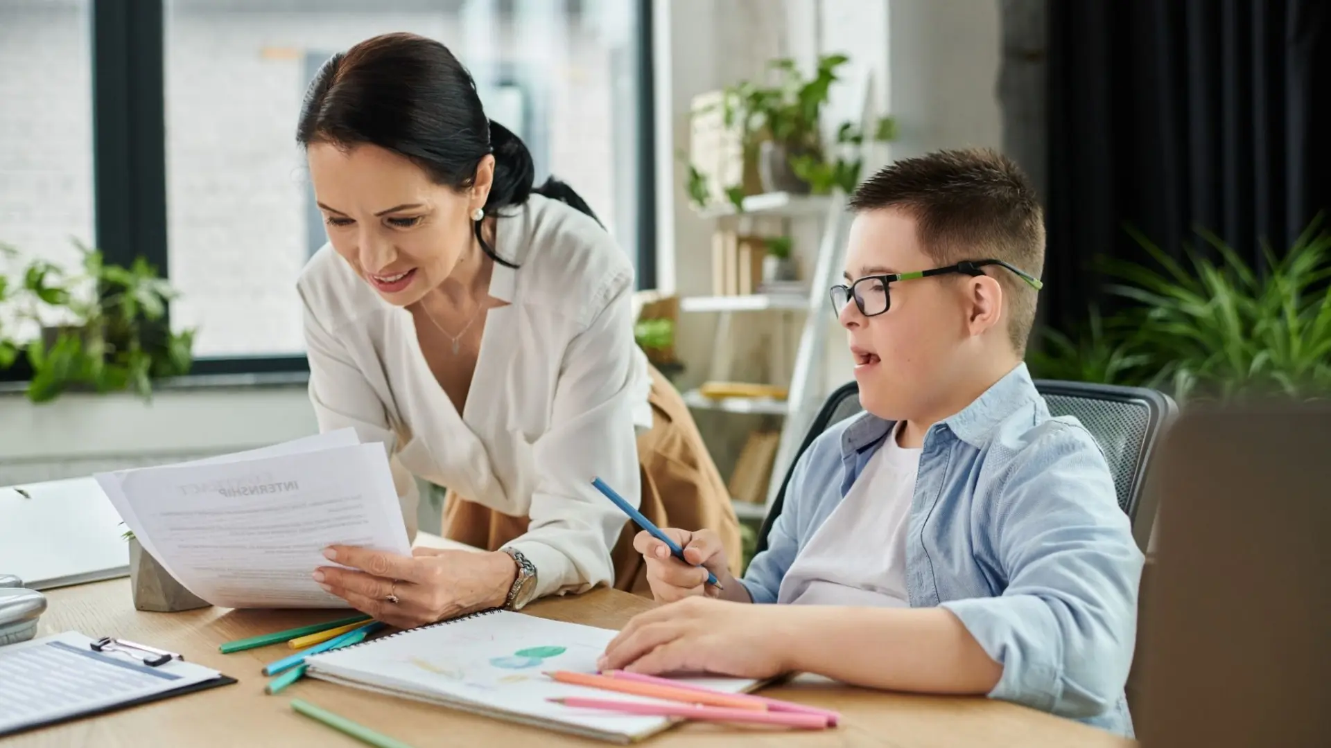 Smiling teacher teaching a student with down syndrome.