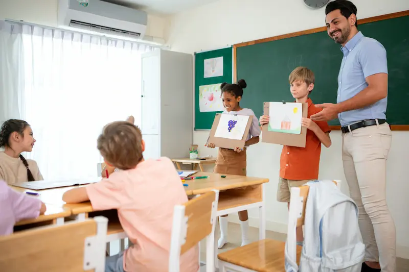 Children presenting their artwork next to a proud teacher.